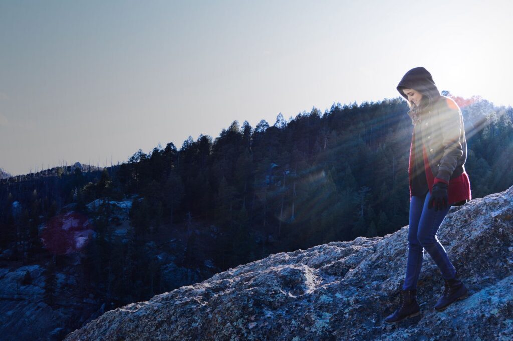 Hiker walking on a rocky mountain slope at sunrise