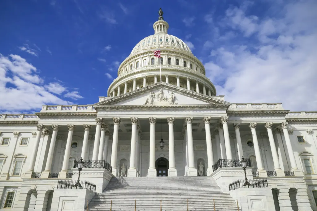 Crowd-control weapons: White dome of the US Capitol against a clear blue sky