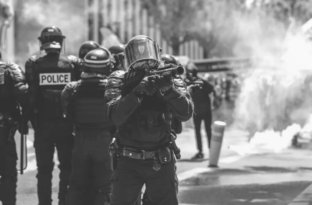 Crowd-control weapons: Line of riot police in helmets facing a street demonstration