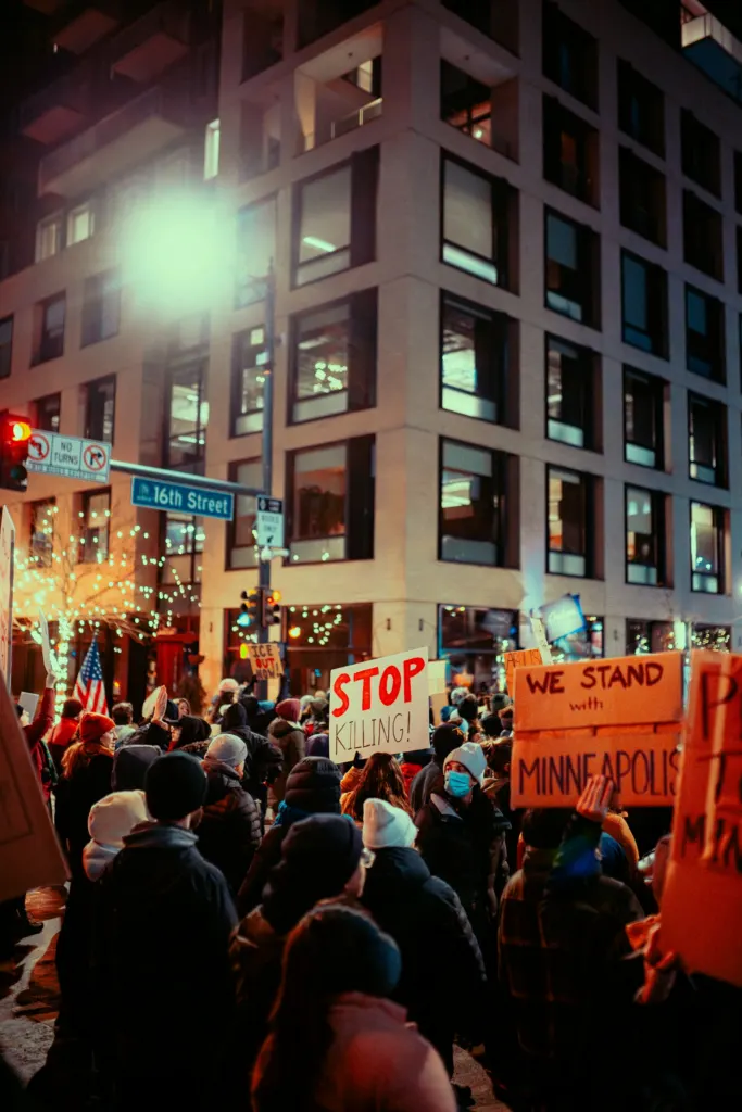 Protesters gathered at night holding signs on a city street