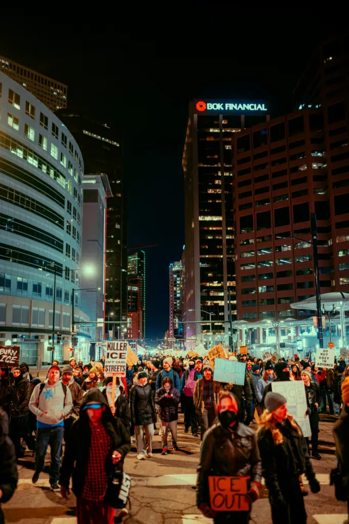 Marchers walking down a downtown street at night with signs