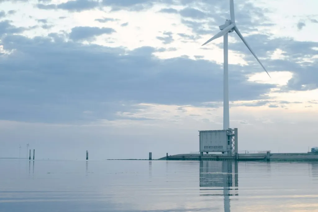 Harrison Ford Trump: Tall offshore wind turbine reflected in still water at dawn