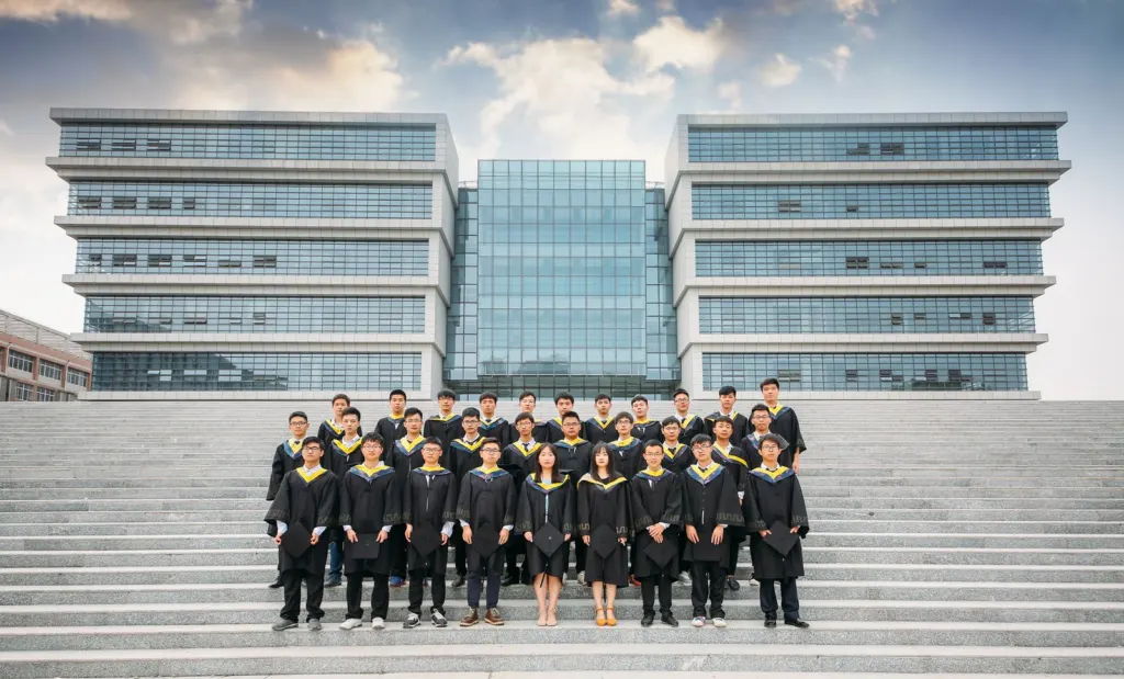 Group of university graduates in gowns posing on campus steps