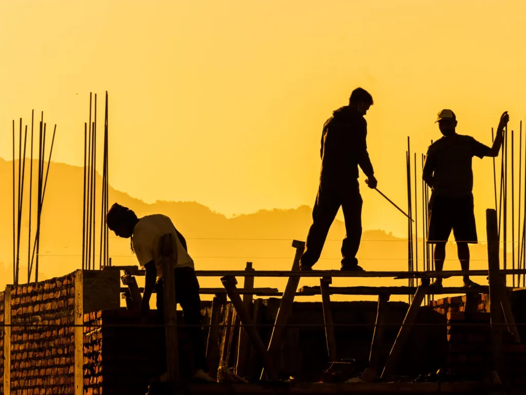 Silhouetted construction workers on a building site at sunset