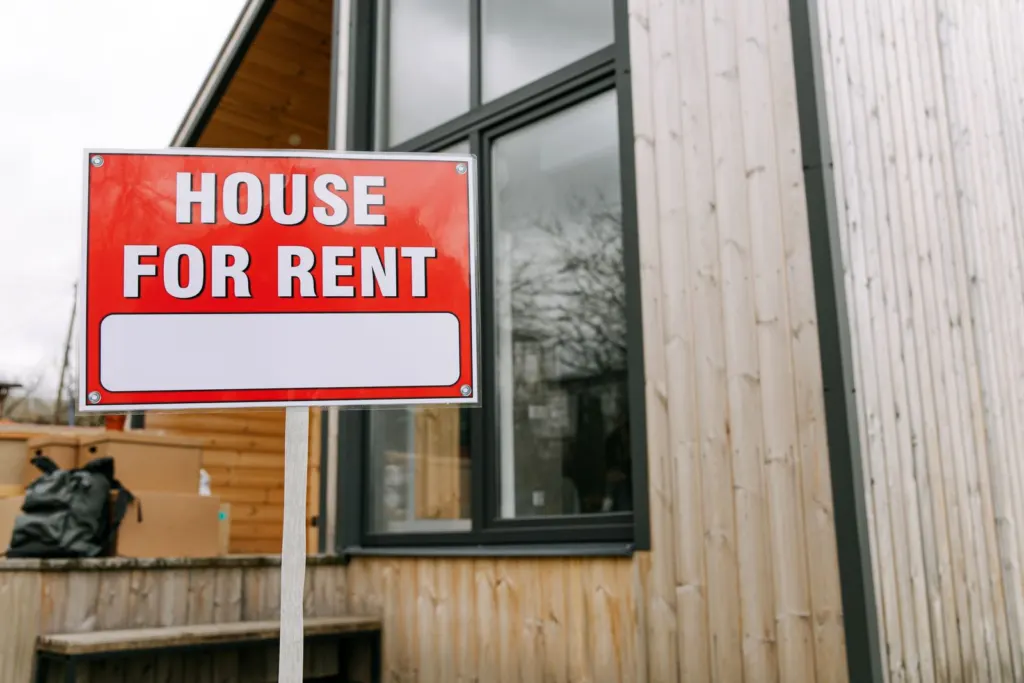 Red house for rent sign placed in front of a home