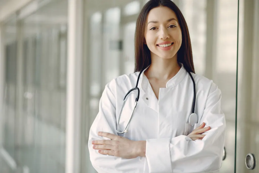 Smiling doctor with stethoscope standing in a hospital corridor