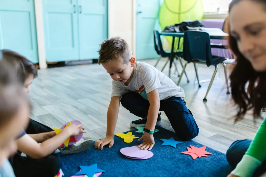 Young children playing with colorful foam shapes in a classroom
