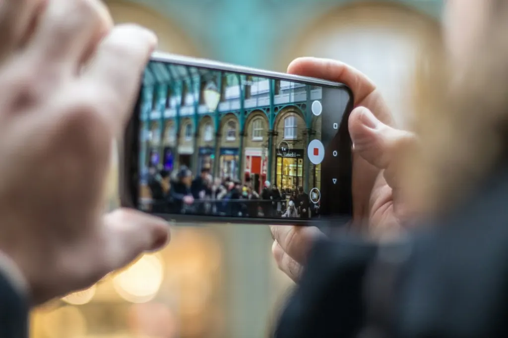 Hand holding a smartphone recording video of people in a street