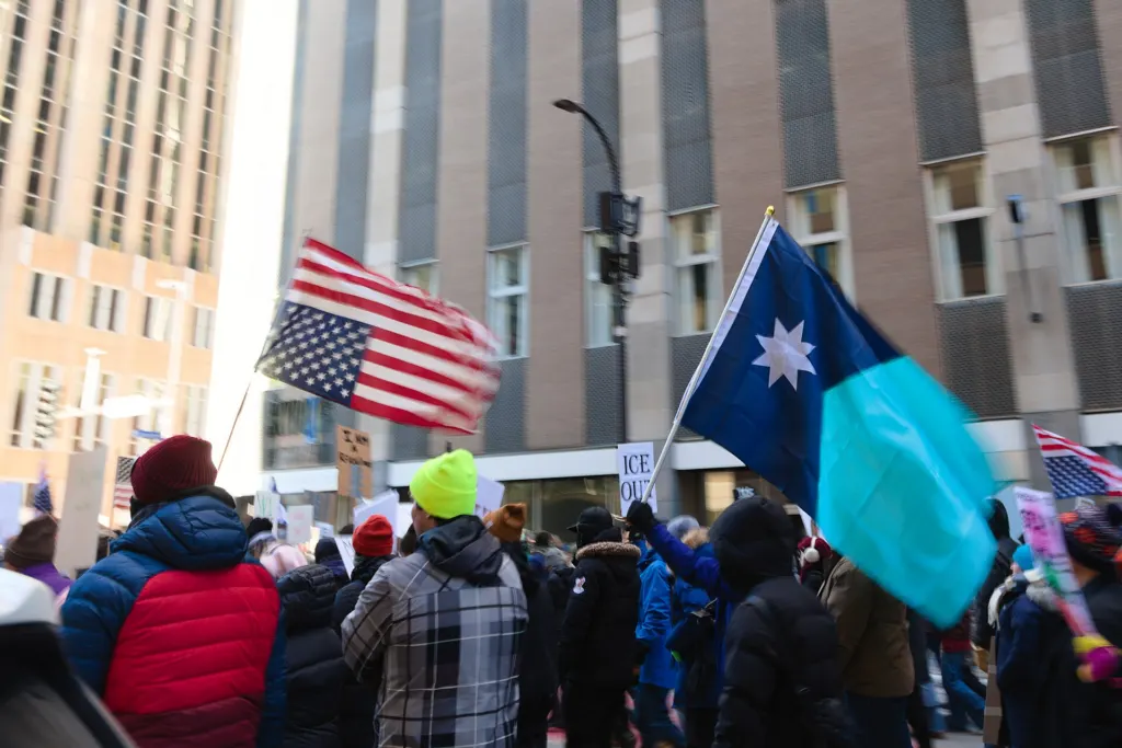 Large crowd carrying flags in a winter protest march through Minneapolis streets