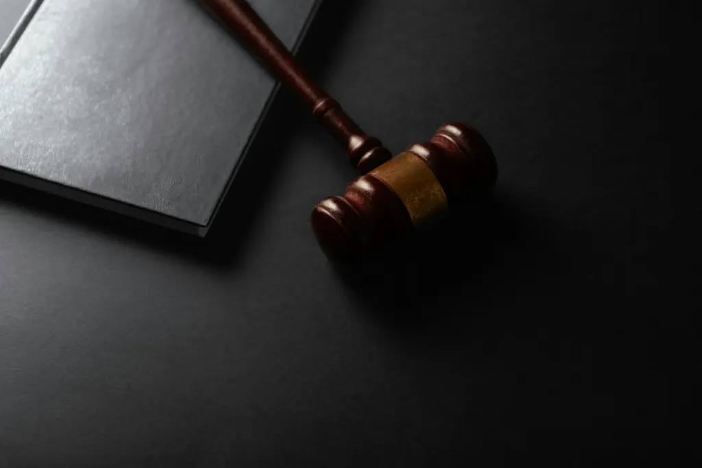 ICE wrongful detention bill: Wooden judge's gavel resting beside a book on a dark table