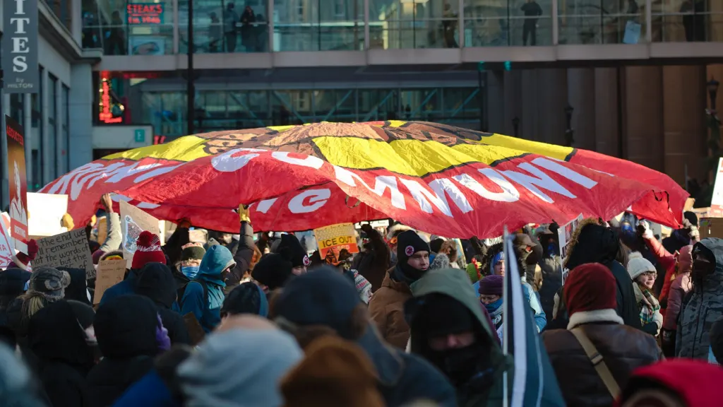 Crowd of protesters in winter coats marching through downtown Minneapolis