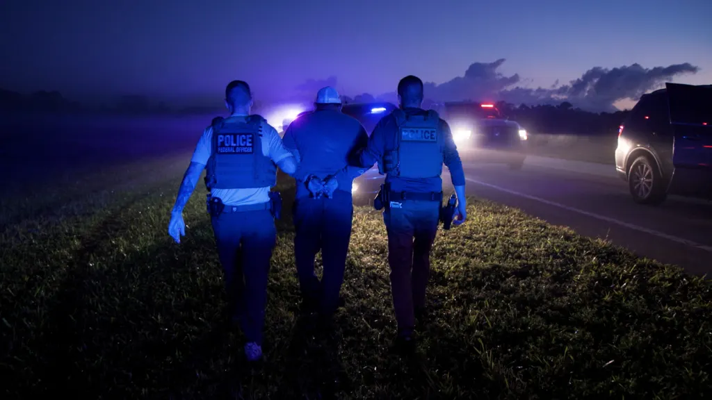 Officers making an arrest beside vehicles during an operation in Florida