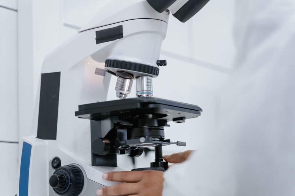 Scientist adjusting a white microscope in a lab