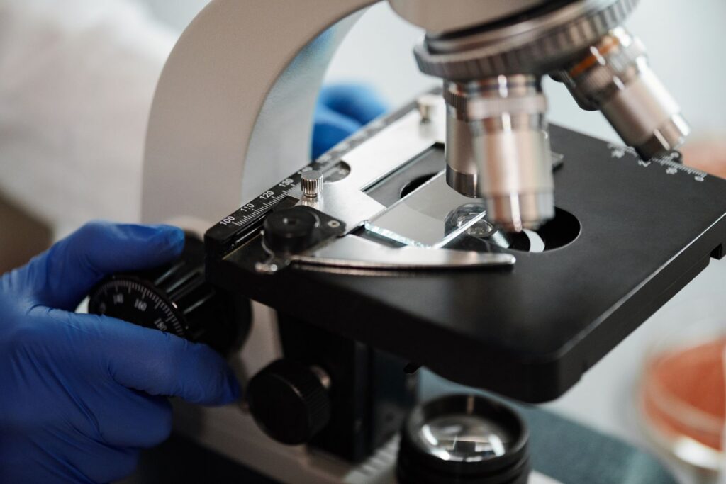 Close-up of a gloved hand adjusting a microscope