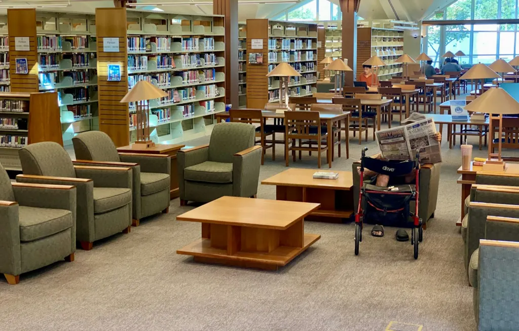 Miley Cyrus donation: Bright reading room with wooden bookshelves, tables and comfortable seating