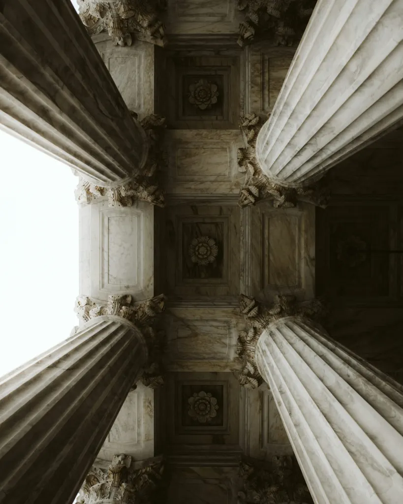 Looking up at stone columns and a decorated ceiling