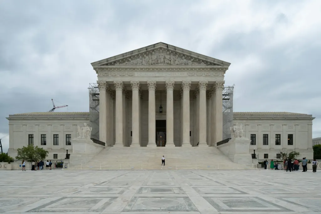 Supreme Court building with tall white columns under a cloudy sky