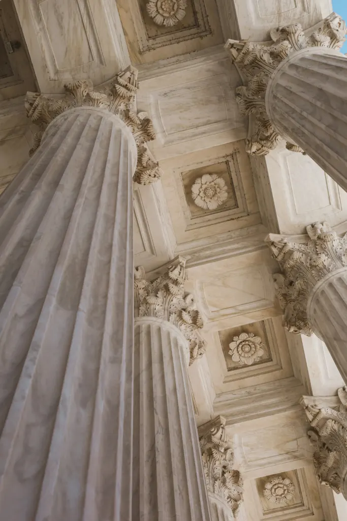 Ornate ceiling with columns and a clock inside a courthouse