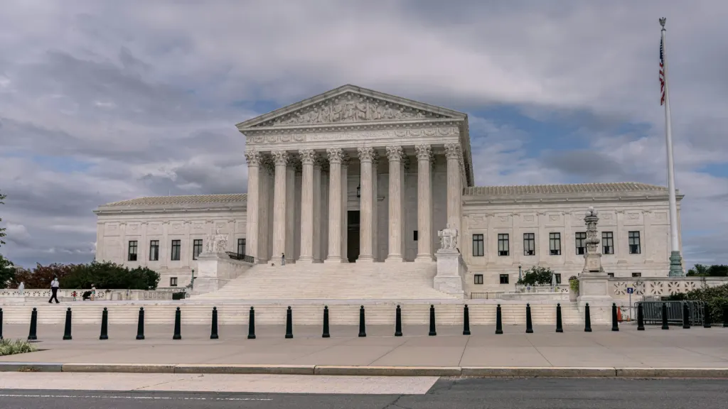 White marble court building beneath scattered white clouds